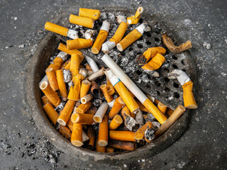 Cigarette butts in overloaded ashtray. Concept of cause of disease and cancer from smoking