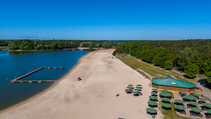beautiful spring and summer day with a view of the lake near the big city, a recreation center with houses and umbrellas, a beautiful sandy beach, water, rest, relaxation, beautiful blue sky