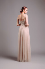 Adorable young woman in backless ivory summer dress. Studio portrait of ginger lady in sleeveless...