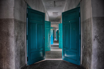 several open doors in an abandoned hospital symmetrically open, turquoise nice as decor or painting on the urbex theme
