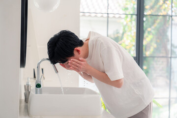 洗面所で洗顔をする若い男性