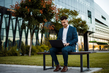 Man Sitting on Bench Using Laptop