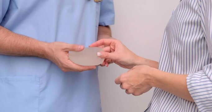 doctor and patient, exam, consultation in clinic office, holding breast enlargement implant in hands, plastic surgery, beauty enhancement, medical Mammoplasty and plastic surgery, mastopexy