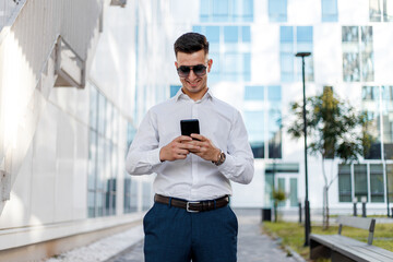 Man in White Shirt and Blue Pants Looking at Cell Phone