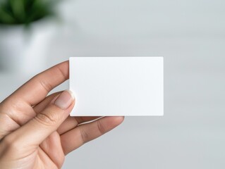Obraz premium Hand holding blank business card in minimalist office setting