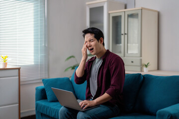 Fototapeta premium Stressed Asian Freelancer Having Headache While Working From Home on Laptop