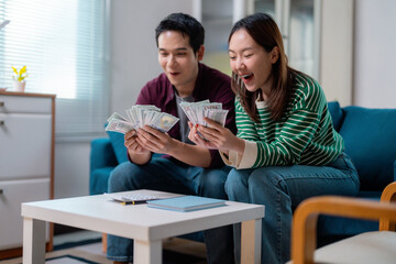Excited Couple Counting Money on Sofa at Home