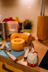 Kitchen timer in the form of a rooster. In the background there is a cutting board, a pumpkin and a knife for peeling vegetables and various kitchen utensils. Cooking at home in the kitchen