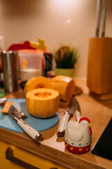 Kitchen timer in the form of a rooster. In the background there is a cutting board, a pumpkin and a knife for peeling vegetables and various kitchen utensils. Cooking at home in the kitchen