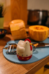 Kitchen timer in the form of a rooster. In the background there is a cutting board, a pumpkin and a knife for peeling vegetables. Cooking at home in the kitchen