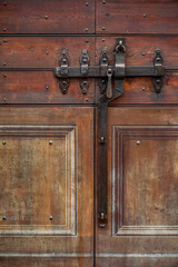 antique black metal door lock with intricate details on a weathered wooden door. The sturdy design symbolizes security, protection, and historical craftsmanship vertical shot