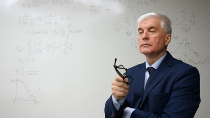Mature man stands at a white board with written formulas.  - Powered by Adobe