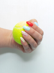 Tennis yellow balls in hand with bright manicure on a white background close-up
