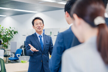 オフィスでの朝礼で挨拶をする管理職の男性