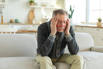 Headache pain. Unhappy middle aged senior man suffering from headache sick rubbing temples at home....