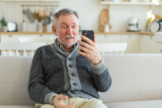 Happy middle aged senior man talk on video call with friends family. Laughing mature old senior grandfather having fun speaking with grown up children online. Older generation modern tech usage