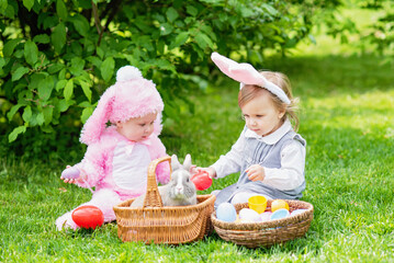 Children play with real rabbit. Laughing child at Easter egg hunt with pet bunny. Little toddler...