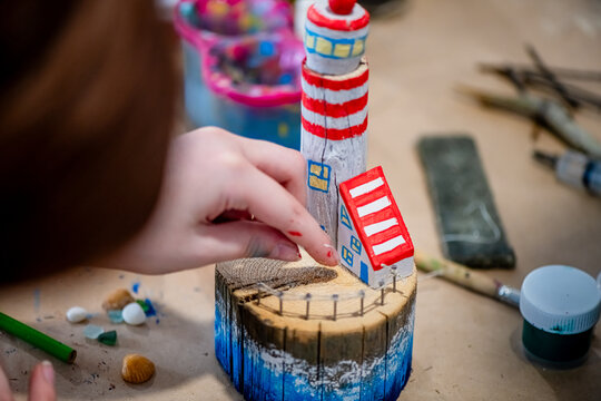 cute teen girl at a master class making a DIY wooden lighthouse made of wood, exhibition of crafts, crafts fair, education, master classes