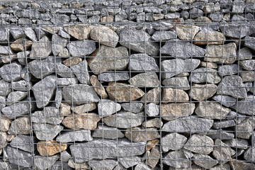 Abstract background of granite stones and wire mesh in a gabion wall