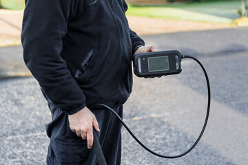 Gas Engineer Wearing PPE in Residential City Street Holding a Digital Combustible Gas Leak Detector