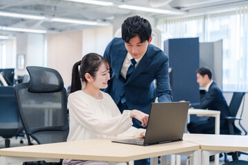 先輩社員から業務を教えてもらう新人の女性