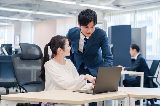 先輩社員から業務を教えてもらう新人の女性