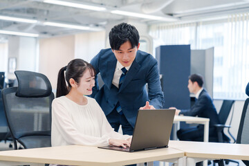 先輩社員から業務を教えてもらう新人の女性