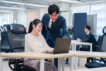 先輩社員から業務を教えてもらう新人の女性