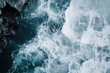 Fototapeta premium Foaming ocean water flows with dark rocks along the coast