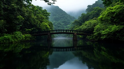Fototapeta premium Serene Bridge in Lush Valley - Tranquil scene of a wooden bridge reflecting in a calm lake, surrounded by lush green mountains. Perfect for nature, travel, and serenity themes