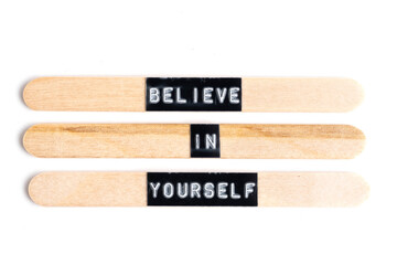Believe in yourself words written on wooden sticks isolated on white background.