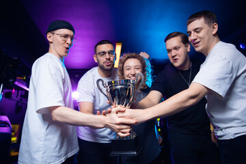 Diverse young team celebrates esports victory together with trophy