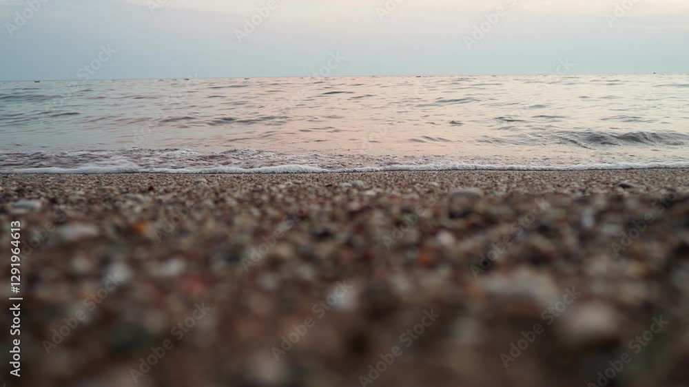 Poster Soft waves roll onto a sandy beach as twilight sets in. The calm sea reflects the fading light creating a serene atmosphere for evening relaxation. Reflection of pink rays. Mediterranean Adriatic Sea.