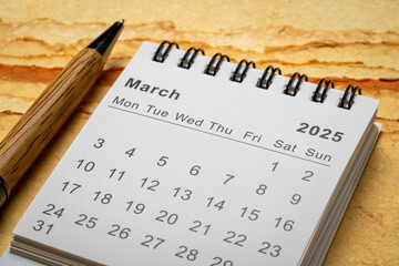 March 2025 - small spiral desktop calendar, time and business concept