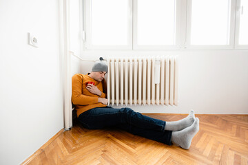 Person sitting against wall holding knees in a bright room