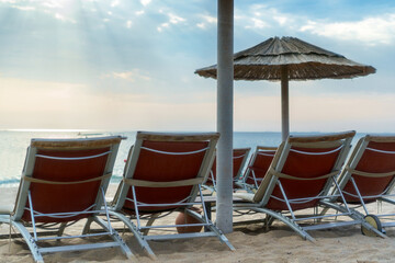 Serene beachside loungers under straw umbrella at sunrise with tranquil ocean view