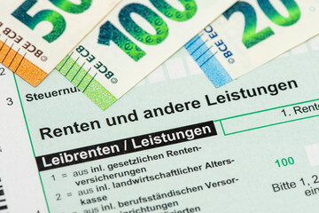 Auf einem Steuerformular für Renten liegen einige Euro Geldscheine