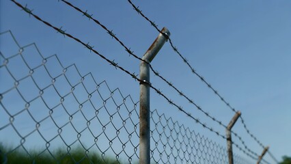 Close-up of barbed wire fence against a clear blue sky