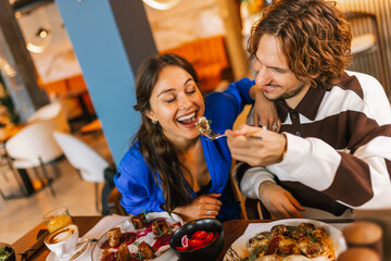 Couple feeding eachother in a restaurant with delicious food.