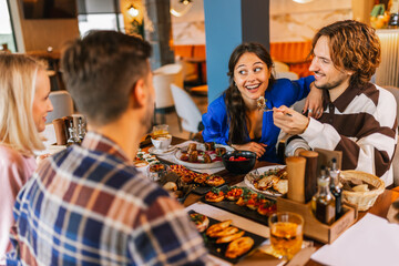 Couple feeding eachother in a restaurant with delicious food.
