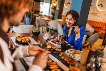 Friends gathered in a restaurant to eat delicious food, talk, drink and hang out.