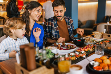 Family of three eating in a restaurant delicious food. Food and drink concept.