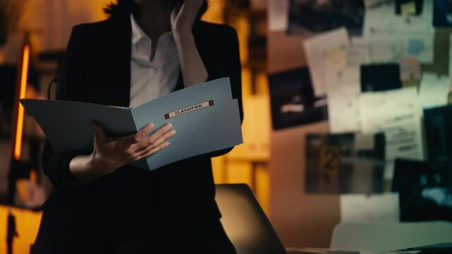 Female detective speaks on the phone while holding a folder with classified data