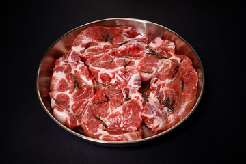 Freshly cut meat in a metal casserole with herbs ready to cook