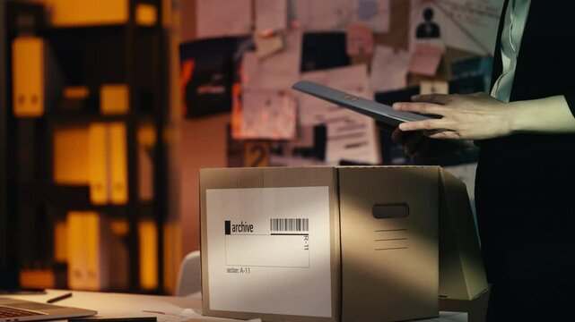 Detective packs documents into an archive box, completing an investigation