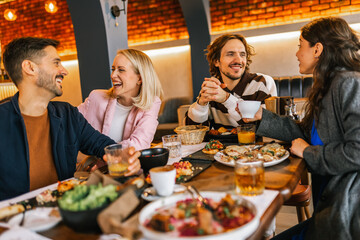 Friends gathered in a restaurant to eat delicious food, talk, drink and hang out.