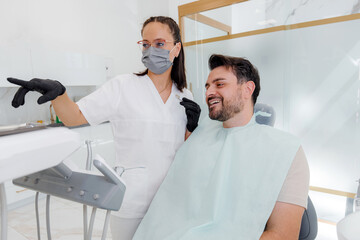 Fototapeta premium Dental consultation in a modern clinic with a dentist showing a patient the treatment plan