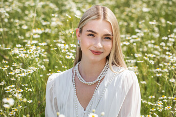 Portrait of a young beautiful blonde in a chamomile field