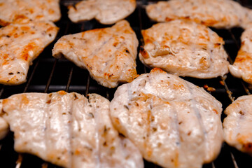 Grilled chicken pieces with grill marks cooking on barbecue