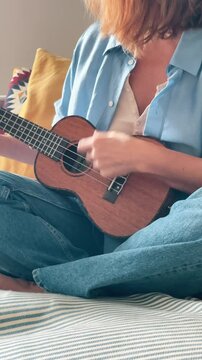 Close up Ukulele or uke string instrument video popular on Hawaii islands. Woman playing nylon strings during music lessons in living room. Musical education and art people concept vertical 4K footage